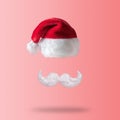 White hipster mustache and hat of Santa Claus on pink background. New Year or Christmas minimal concept