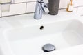 White home sink in the bathroom with metal water faucet.