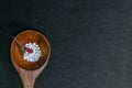 White homeopathy pills in Wooden spoon with pink flower bud on dark background. Natural medicine concept