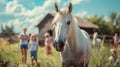 White horse and children in the meadow near the stables