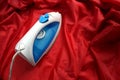 White hot iron ironing red crumpled fabric Royalty Free Stock Photo