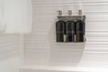 Hotel shower body wash, liquid soap, hair conditioner, and shampoo bottles in chrome dispenser with white towel on a wall