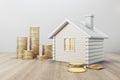 White house with golden coin stacks on wooden and concrete background. Mortgage and loan concept. Royalty Free Stock Photo