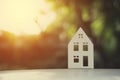 a white house model on a white floor with blurred green leaves background Royalty Free Stock Photo