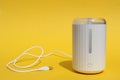 A white humidifier stands on a yellow background.