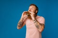 Hungry bearded man eating burger isolated on blue background Royalty Free Stock Photo
