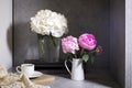 White hydrangea in a glass vase with a small cup of coffee on a book with a notebook on a gray craft background. . Copy space