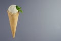 White ice cream cone scoop in waffle cone with green mint leaf on grey background, copy space. Royalty Free Stock Photo