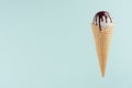 White ice cream in crisp waffle cone with chocolate sauce on pastel green background, mock up, summer food. Royalty Free Stock Photo