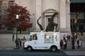 White ice cream van in front of American Museum of Natural History. Dinosaur shaped christmas tree behind the truck.