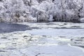 White ice floats on the river on the background of trees covered with snow and hoarfrost. Winter landscape on the lake Royalty Free Stock Photo