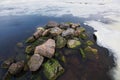 White ice and snow pieces with several stones in river coast water in cold winter morning Royalty Free Stock Photo