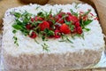 White icing cake with shaved coconut and white chocolate topped with strawberries and raspberries and lavendar.