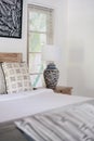 White interior in authentic bedroom with copy space on wall and lamp on bedside table