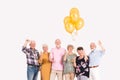 Interior with group of senior happy friends holding bunch of balloons