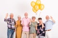 interior with group of senior happy friends holding bunch of balloons