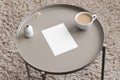 White invitation card mockup with a lagurus and a cup of coffee on the beige table. 5x7 ratio, similar to A6, A5