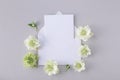 White invitation card mockup from paper blank decorated with fresh flowers in minimal elegant style. Beautiful floral template