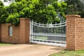 White iron driveway entrance gates in brick fence