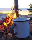 Cup of Coffee by a Campfire. white iron mug by the fire against the sunset by the lake Royalty Free Stock Photo