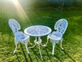 White iron table and chairs at the green field. Royalty Free Stock Photo