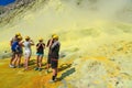 White Island, New Zealand. Tourists in hard hats and gas masks examine molten sulfur pits