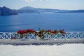 White island balcony with dark pink red Bougainvillea flower foreground in front of scenic mediterranean sea view and caldera