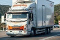 A white Isuzu truck refrigerator with a large van driving by the highway