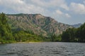 White Iyus river among hills and rock massifs. People float down the river on catamarans