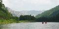 White Iyus river among hills and rock massifs. People float down the river on catamarans