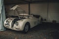 White Jaguar XK120 Roadster on display with its hood open.