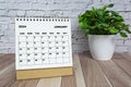 White January 2024 calendar on office wooden desk with potted plant.