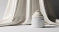 A white jar with a swirly cream on top sitting in front of a draped fabric background Royalty Free Stock Photo