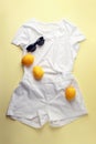 White jeans, white shirt, sunglasses and lemons on yellow background. Women`s stylish spring summer outfit. Trendy clothes. Flat