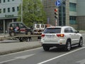 White Jeep Grand Cherokee and a flatbed tow truck in a Moscow street.