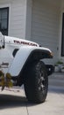 White Jeep Rubicon in front of a house from the side, close-up, vertical