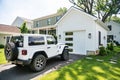 white Jeep Rubicon is parked outside white garage Royalty Free Stock Photo
