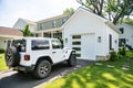 white Jeep Rubicon is parked outside white garage