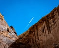 White jet contrail over rocky red cliff