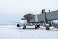 White jetliner at the boarding bridge at winter airport apron