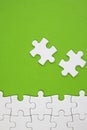 White jigsaw puzzle pieces on green background with negative space Royalty Free Stock Photo