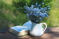 White jug with bouquet of forget-me-nots on wooden table