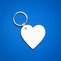 White key ring on blue background. Key chain for your design. Hanging accessory or souvenir.  Heart shape Royalty Free Stock Photo