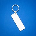 White key ring on blue background. Key chain for your design. Hanging accessory or souvenir.  long square shape Royalty Free Stock Photo