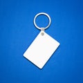 White key ring on blue background. Key chain for your design. Hanging accessory or souvenir.  Rectangle shape Royalty Free Stock Photo