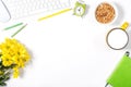 White keyboard, mouse, colorful stationery, yellow flowers, plate with granola and large cup of milk on white background