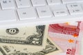 White keyboard over dollar and euro banknotes