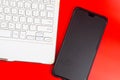 White keyboard with smartphone isolated on red background. Royalty Free Stock Photo