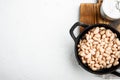 White kidney beans, in cast iron frying pan, on white stone  surface, top view flat lay, with copy space for text Royalty Free Stock Photo