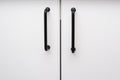 White kitchen cabinets with metal black pulls or knobs, handles on the doors close up background Royalty Free Stock Photo